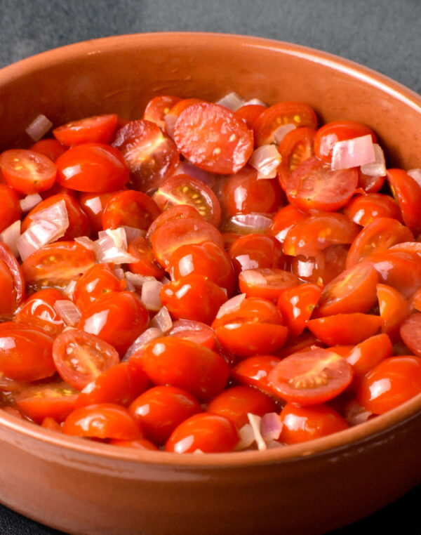 cherry tomatoes and onions cooking in a cazuela.